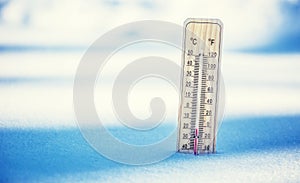 Thermometer on snow shows low temperatures under zero. Low temperatures in degrees Celsius and fahrenheit. photo