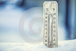 Thermometer on snow shows low temperatures under zero. Low temperatures in degrees Celsius and fahrenheit.