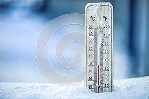 Thermometer on snow shows low temperatures - zero. Low temperatures in degrees Celsius and fahrenheit. Cold winter weather - zero.