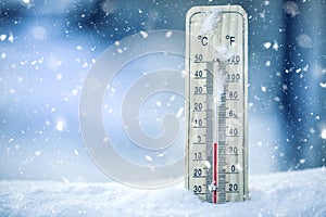 Thermometer on snow shows low temperatures - zero. Low temperatures in degrees Celsius and fahrenheit. Cold winter weather - zero photo