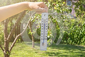 Thermometer in a woman's hand. Extreme hot weather