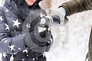 Thermos and cold season concept - A woman pours a hot drink. Couple on a winter holiday