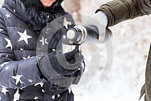 Thermos and cold season concept - A woman pours a hot drink. Couple on a winter holiday