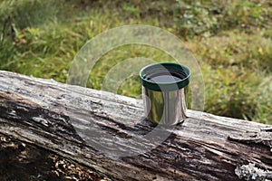Thermos green plastic stainless steel mug on a log