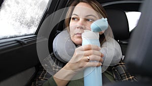 Thermos in the hands of a woman in the car in winter. Travel concept. 3840x2160