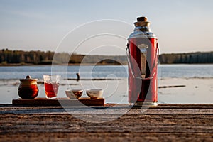 Thermos with tea and teacups in nature, camping