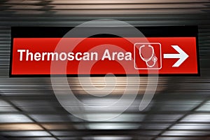 Thermoscan Area red sign with arrow direction hang from ceiling at the airport for outbreak control situation at passengers