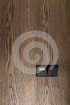 Thermostat mounted on oak wall. Modern programmable thermostat. Efficient automated heating system concept.