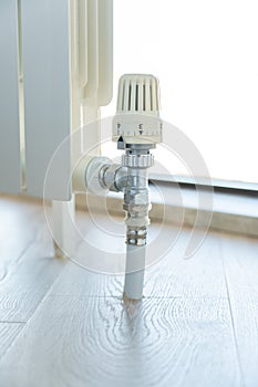 Thermostat valve on white radiator close up photo
