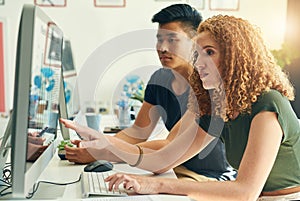 Theyll figure it out together. two young creative businesspeople working on a computer in their office.