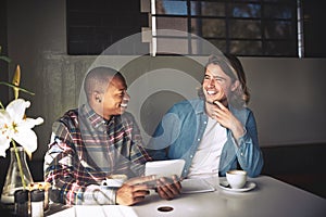 Theyre always connected. two friends using a tablet while having coffee in a coffee shop.