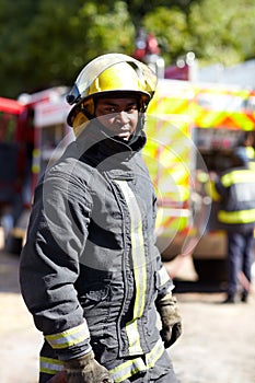 Theyre cool under pressure. Portrait of an african fireman standing with his team in the background.