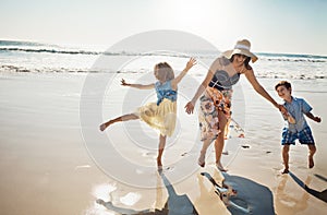 Theyre a family of beach fanatics. a mother bonding with her two little children at the beach.