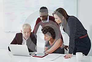 Theyre four of the best. a group of businesspeople discussing work over a laptop.