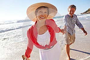 Theyre a fun loving couple. a mature couple enjoying a late afternoon walk on the beach.