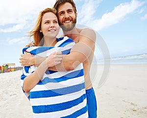 Theyre so happy together. a young man embracing his girlfriend on the beach.