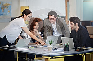 Theyre innovators in the biz. designers talking together over laptops in an office.