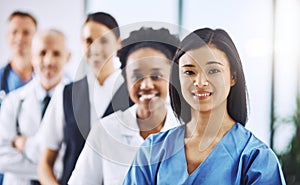 Theyre lining up to help. Cropped portrait of an attractive young female doctor standing at the front of a queue of