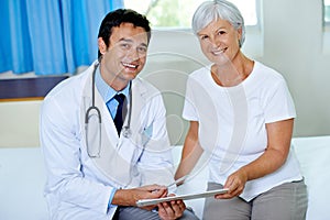 Theyre pleased with the results. Portrait of a handsome young doctor going through a chart with a senior patient.