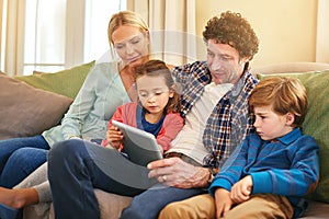 Theyre a tech savvy family. a family browsing together on a digital tablet at home.