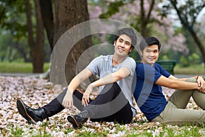 Theyre always there for each other. Cute young gay Asian couple smiling together while sitting in the park.