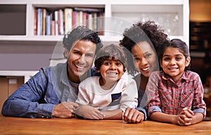 Theyre a tight-knit family. Portrait of a happy family of four sitting together at home.