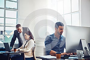 Theyve got all the attributes of a productive team. young businessman using a computer at work with his colleagues in