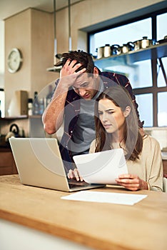 Theyve still got quite a few outstanding bills to pay. a young couple looking anxious while using a laptop and going