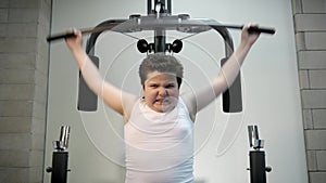 Thick angry kid boy trains in gym fat burning. children concept overweight tenacity purpose