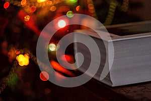 thick book on the background of a christmas tree with christmas lights