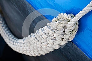 Thick braided rope hangs to the side of a metal ship\'s hull