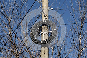 A thick coil of fiber optic cable on a concrete pole.