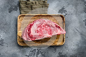 Thick cut raw beef rib eye. Marbled organic meat ribeye steak, on gray stone background, top view flat lay