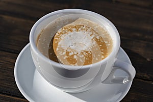 Thick foam of hot coffee cappuccino on wooden table, closeup. Milk foam cappuccino, latte