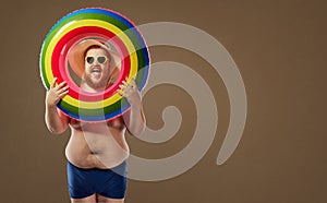 Thick funny man smiling in a swimsuit with an inflatable circle.