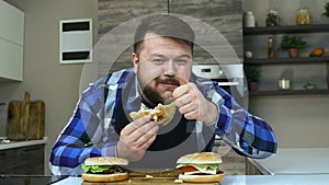 Thick guy with a beard eats a piece of hamburger and shows thump up or like. The food is very delicious. The plump guy