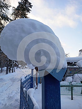 A thick layer of snow lies on the pillar. After a heavy snowfall