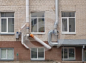 Thick, powerful ventilation pipes air conditioners  mounted on the old white bricks school wall