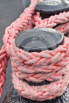Thick rope and black mooring bollard. Detail of port. Yachting