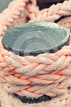 Thick rope and black mooring bollard. Detail of port. Yachting