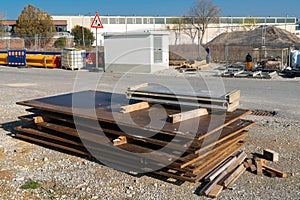 Thick, rusty metal plates stacked on a construction site.