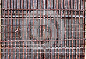 thick rusty old grate on the window of the house. frequent rods