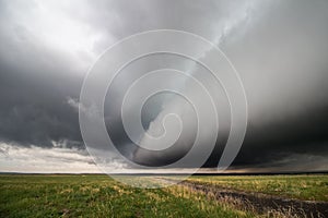A thick shelf cloud approaches as a powerful storm moves across a field.