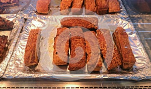 Thick slices of crispy roasted pork belly for sale on display in thermal counter in deli department of supermarket