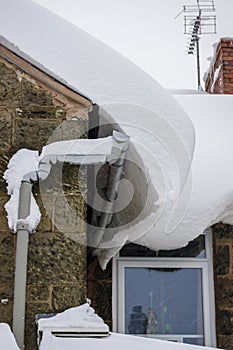 Thick snow causing damage to house roof and guttering.