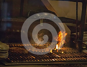 Thick Steaks Sizzling on a Grill over top the Flames