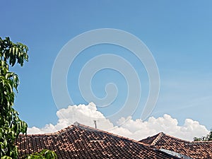 The thick white clouds looked so beautiful above the roofs of people& x27;s houses photo