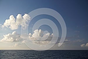 Thick white clouds over the horizon in a deep blue sky somewhere in the North Pacific Ocean