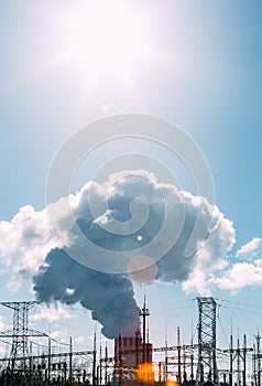 Thick white smoke from the chimney of a nuclear power plant. High-voltage wires