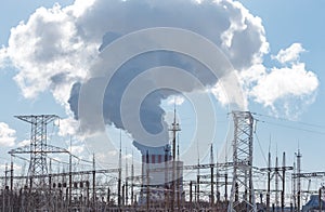 Thick white smoke from the chimney of a nuclear power plant. High-voltage wires